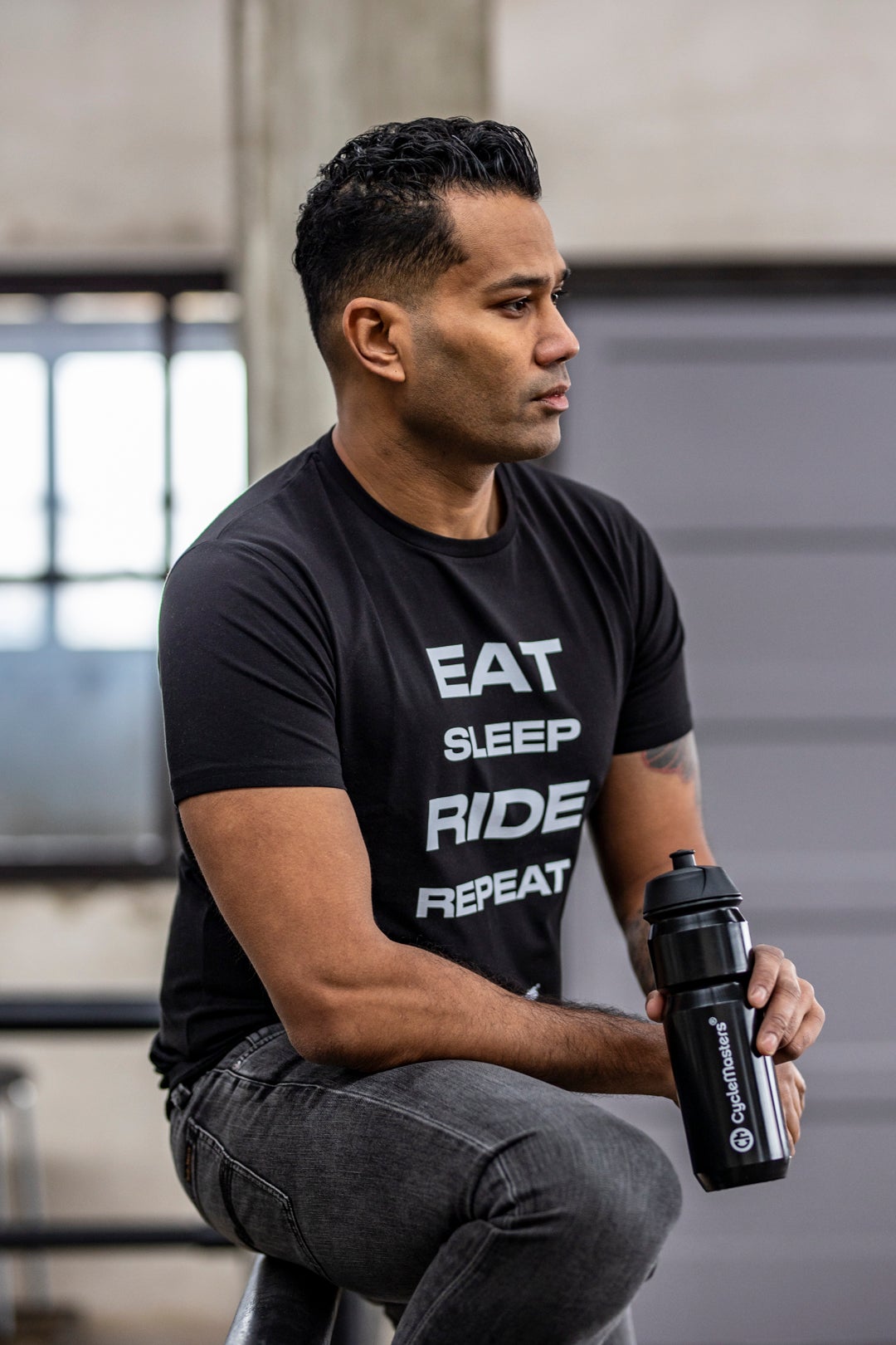 A man wears a black CycleMasters t-shirt and water bottle