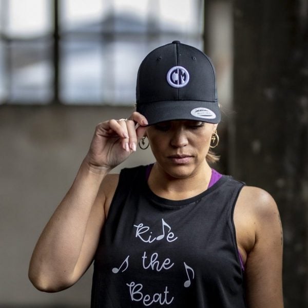 A woman wears a black CycleMasters cap and tanktop