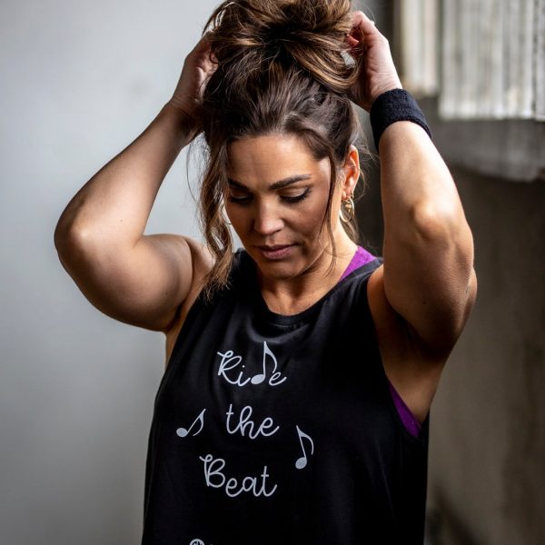 A woman wears a CycleMasters tank top and a sweatband